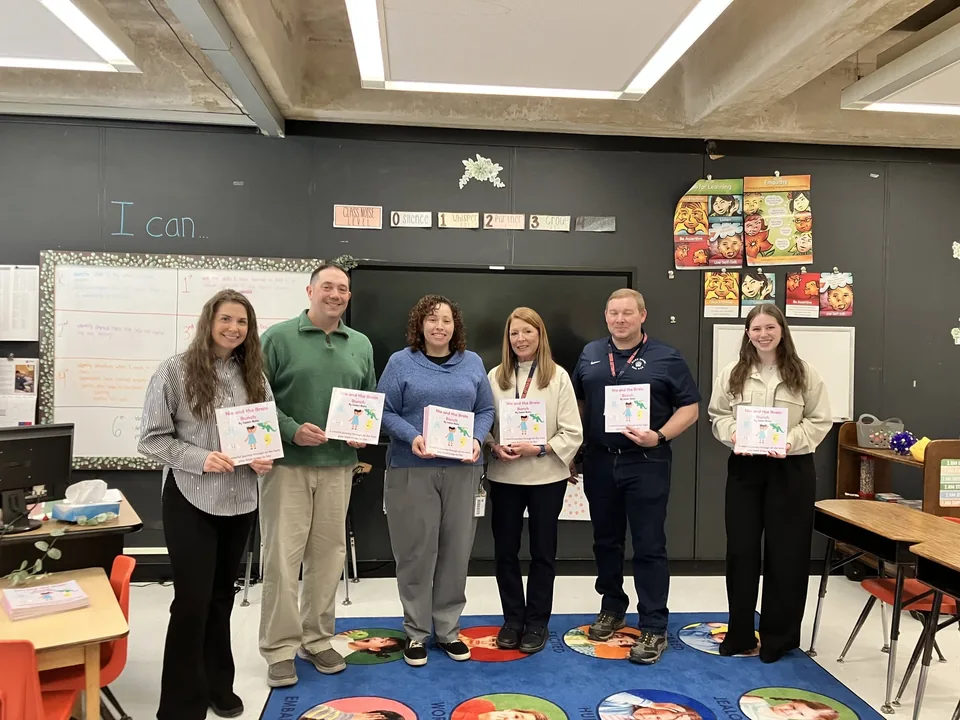 A group holding copies of Nia and the Brain Bunch in a classroom