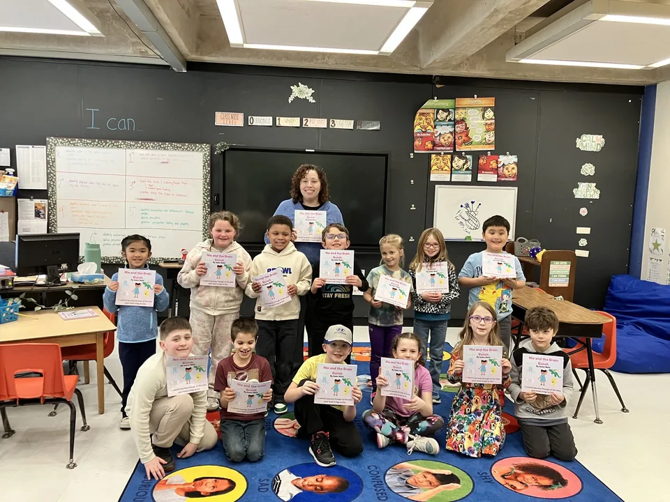 A group of children and an adult holding copies of Nia and the Brain Bunch in a classroom